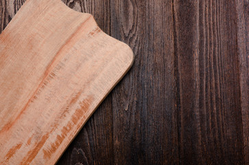 Wood board on wooden dark desktop. View from the top.