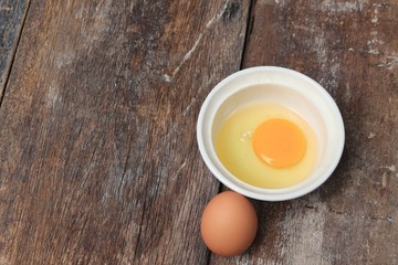 Raw egg in a bowl selective focus on wooden table