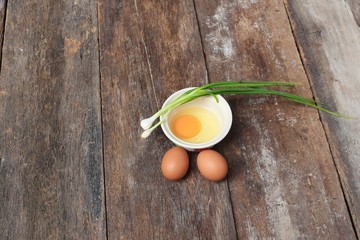 Raw egg in a bowl selective focus and onion on wooden table