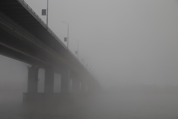 The bridge over the river lost in the thick fog.