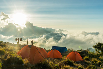 Mountain Camping. Tent camp on the crater rim of Mount Rinjani, Lombok, Indonesia. Sun is setting in the clouds, tents glow bright orange. 29. Auugust 2016