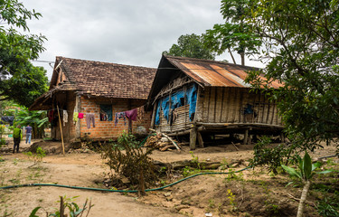 Fototapeta na wymiar Vietnamese Farm Village Housing. Two wooden houses in a rural ethnic minority farm village in central Vietnam. Taken near Kon Tum, Vietnam.