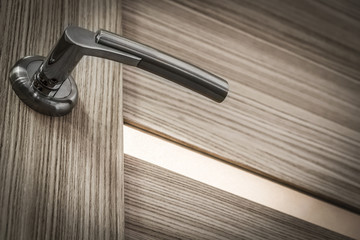 Naklejka premium Chrome-plated metal handle interior door close-up.