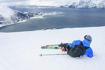 Skitourengeher genießt die Aussicht auf die winterliche Fjordlandschaft am Polarkreis