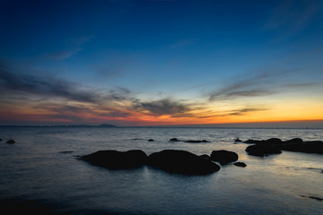 Fototapeta na wymiar Rocks at sea side with silhouette theme sunset sky