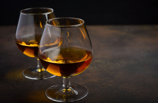 Glass of brandy or cognac on the old rusty background, selective focus, horizontal, copy space