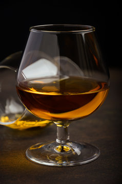 Glass of brandy or cognac on the old rusty background, selective focus, vertical