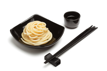Noodles in black ceramic dish stand on white table background wi