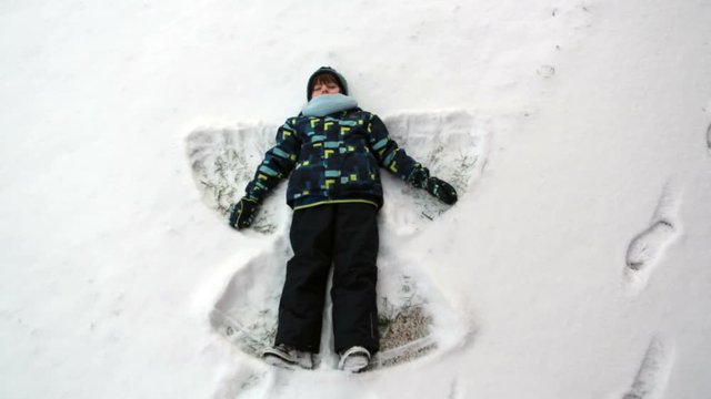Little sweet child, boy, lying on north pole snow, making snow angel, winter time