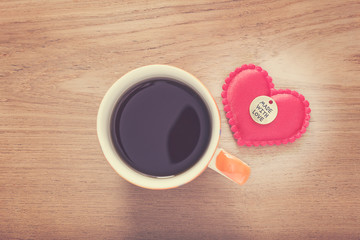 felt heart with Made With Love button and cup of coffee on woode
