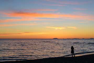 silhouette of woman standing alone on the beach at sunset