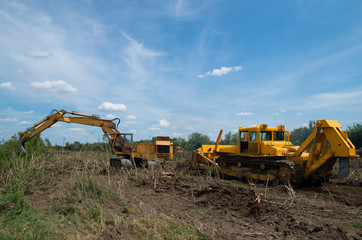 Digger and bulldozer clearing forest land.