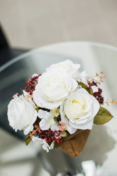 artificial white flowers made from cloth with steel jug ont the glass table 