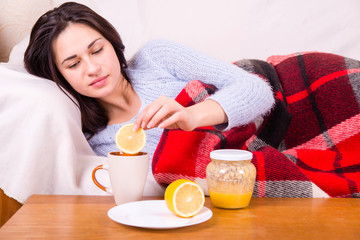 sick girl under a blanket treated tea with lemon
