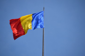 Powiewająca rumuńska flaga na tle błękitnego nieba.