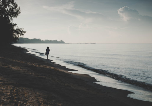 Silhouette of woman walking on the beach background with vintage filter