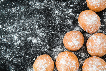 Soft, delicious fresh doughnuts sprinkled with powdered sugar on the black background. Christmas time. Homemade pastries.