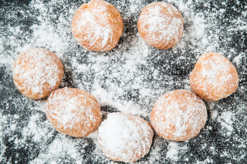 Soft, delicious fresh doughnuts sprinkled with powdered sugar on the black background. Christmas time. Homemade pastries.