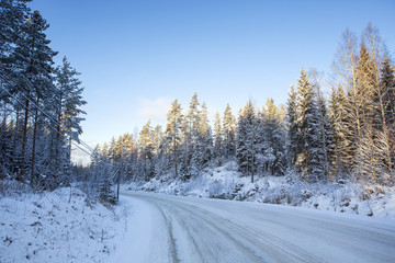 Traveling to the winter wonderland. An image of a snowy road in the countryside on a sunny winter day.