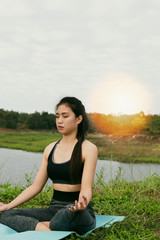 Fototapeta na wymiar young woman meditates while practicing yoga outdoor in park, re