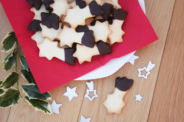 Biscotti al burro glassati al cioccolato a forma di stella su piatto su tavolo di legno