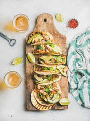 Healthy corn tortillas with grilled chicken, avocado, fresh salsa, limes on wooden board and beer...