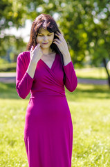 Obraz premium Young brunette girl with freckles in red dress in the summer garden 