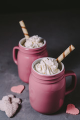 Two pink mugs with hot chocolate and cream on a gray concrete background. Drinks for a loving couple. The concept of Valentine's Day.