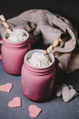 Two pink mugs with hot chocolate and cream on a gray concrete background. Drinks for a loving couple. The concept of Valentine's Day.