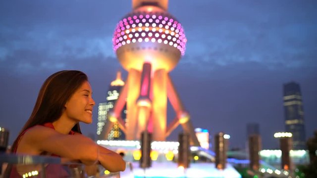 Shanghai woman or tourist looking at city lights at night by Oriental Pearl Tower in Pudong, China. Multicultural Asian Chinese / Caucasian young woman professional in financial district.