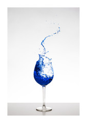 blau farbener Wassersplash im Glas mit Spritzern - Liquid Art, Weinsplash im Glas