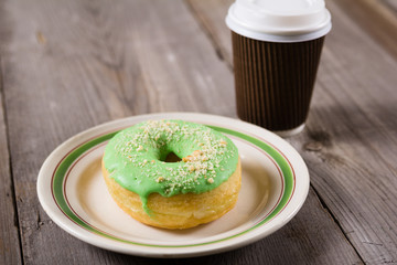 fresh donut and take away coffee, wooden background with copy space