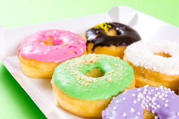 Strawberry, chocklate and other donuts in paper box on blue background