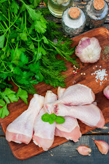 Raw chicken drumsticks on a wooden board, top view