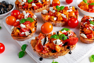 Tasty Traditional Tomato bruschetta with feta cheese topping, fresh basil and balsamic vinegar