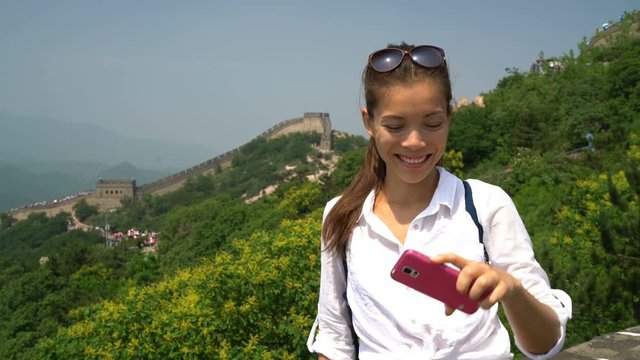 Great Wall of China. Woman tourist taking selfie photo at famous Badaling during travel holidays at Chinese tourist destination. Woman tourist taking picture using smart phone during Asia vacation.