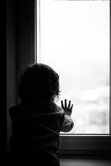 a little boy looks in black and white window