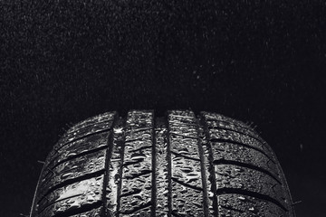 Studio shot of a set of summer, fuel efficient car tires on black background. Covered in wated...