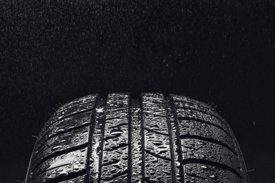 Studio shot of a set of summer, fuel efficient car tires on black background. Covered in wated droplets, rain or aquaplaning concept. Contrasty lighting and shallow depth of field