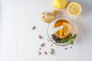 A glass cup of green natural tea with ginger, lemon, mint and honey on wooden rustic background. Healthy drink.