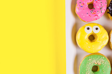 Six colorful round donuts in the box. Flat lay, top view.