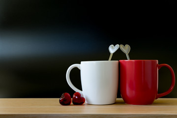 Valentine's day concept with hearts and cups on wooden table in black background