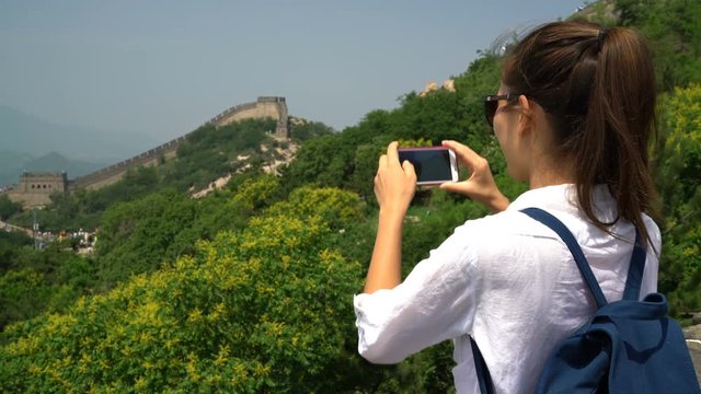 Great Wall of China. Tourist taking photo at famous Badaling during travel vacation holidays sightseeing Chinese tourist attractions. Woman tourist taking picture using smart phone in Asia.