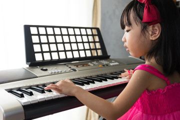 Asian Chinese little girl playing electric piano keyboard