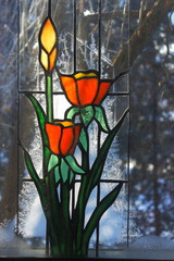 glas in lood raam van bloemen op de achtergrond van de winter, vorst en bomen