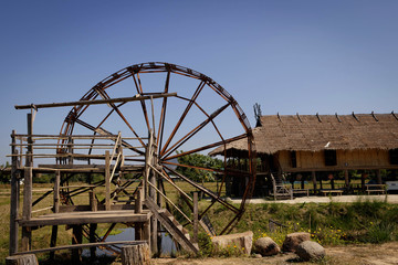 Wood turbine beside rice field.
