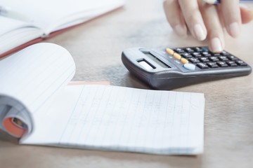hand typing on a calculator during tax season with a notebook in the foreground
