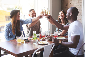 Young group of smiling friends clinking glasses