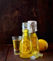 Limoncello in a bottle on a wooden background.Tradtitional italian homemade lemon beverage.
