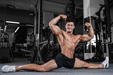 Fototapeta na wymiar Splits stretches man stretching legs in the gym handsome fitness